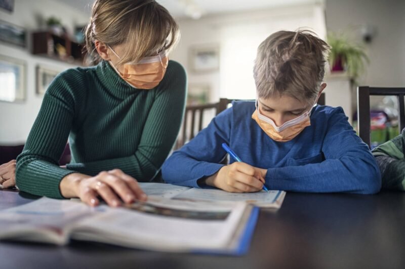 Mother homeschooling her son wearing face masks
